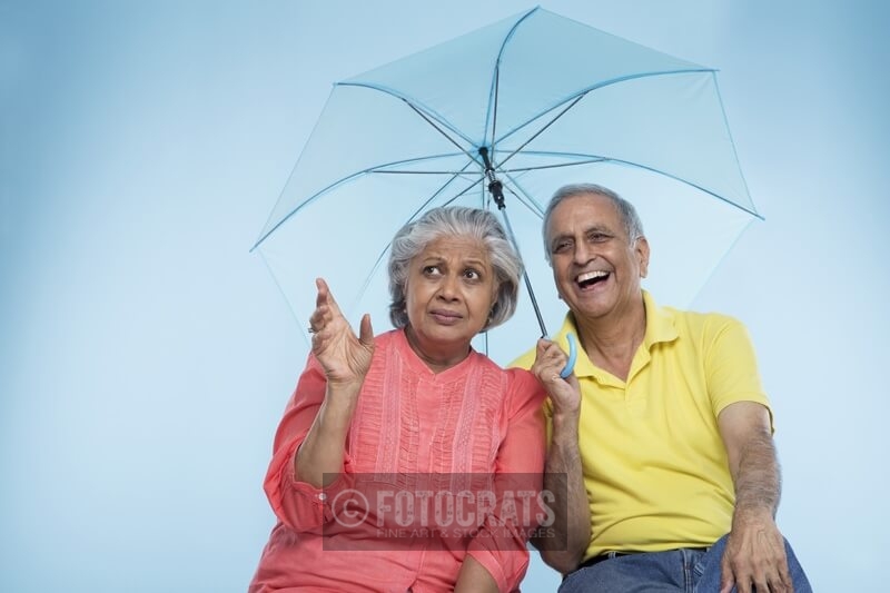 old couple sitting under umbrella 