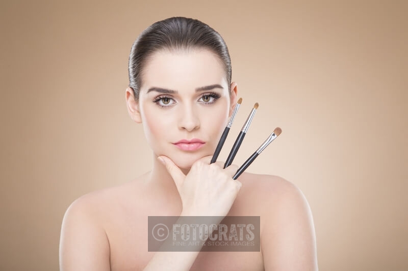 girl posing with make up brush while looking at the camera