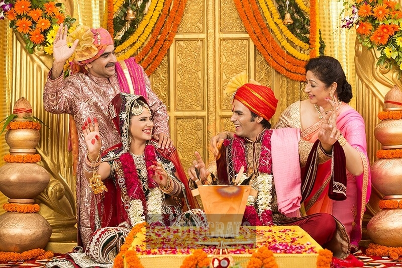 indian bride and groom sitting with parents at mandap