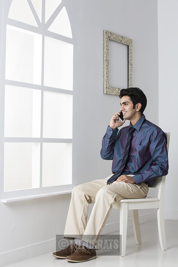 man sitting on chair talking on mobile phone