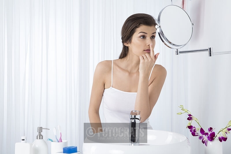 woman checking pimple on her face 