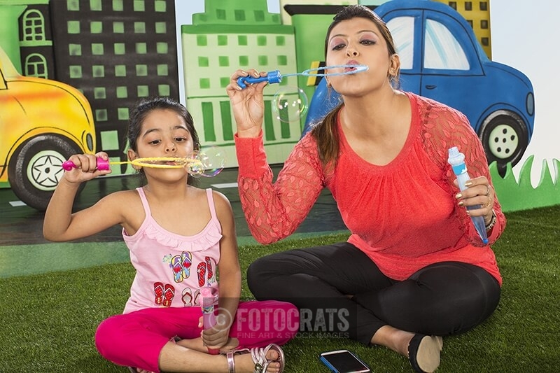 mother and daughter blowing bubbles in the park