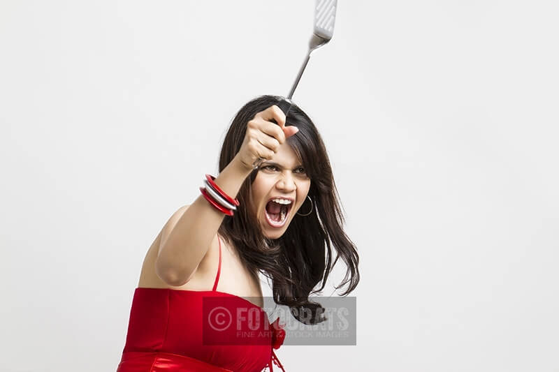 young woman shouting with holding spatula in hands
