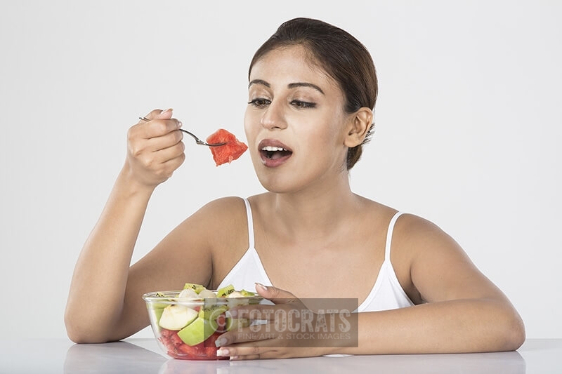 young woman eating fruit salad