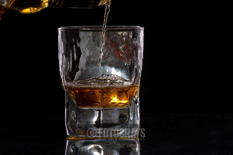 whiskey pouring from a bottle into a glass