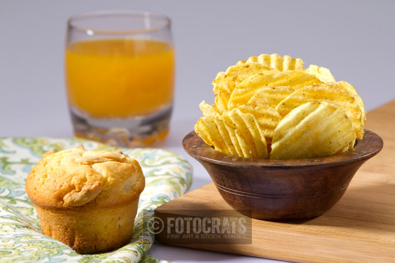 muffin,chips and a glass of juice on the table