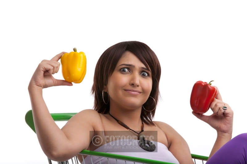 lady holding different coloured capsicums