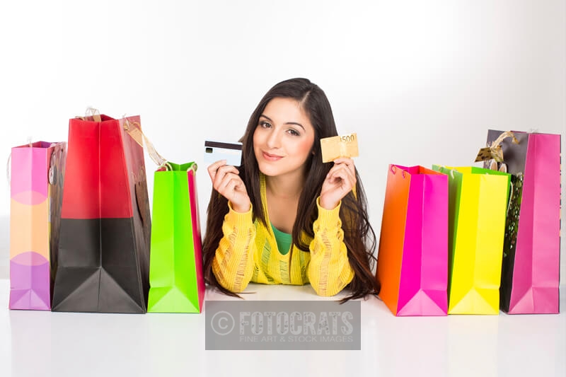 girl lying on the floor with shopping bags holding credit cards