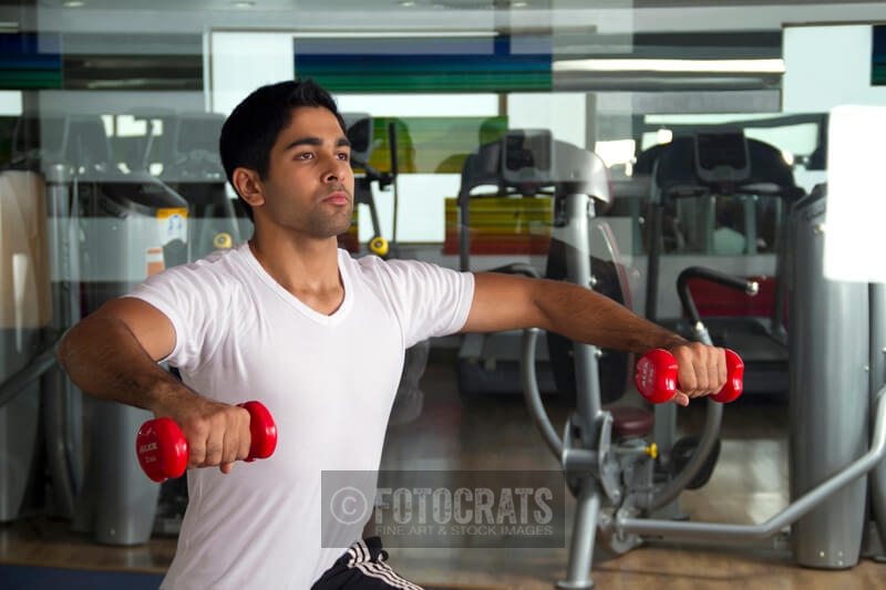 young man lifting light red dumbbells