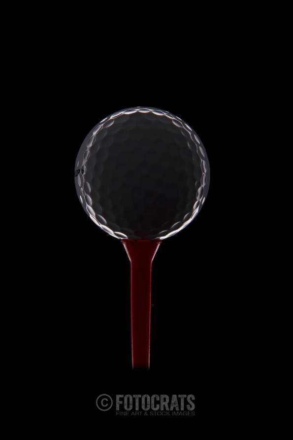 golf ball on golf tee with dark background 