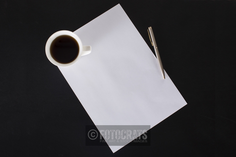 coffee mug and pen lying on paper