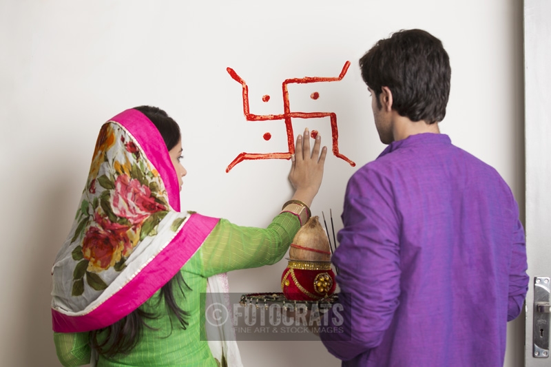 couple making swasthik in their new home 