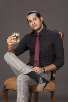 man in formals posing with a drink 