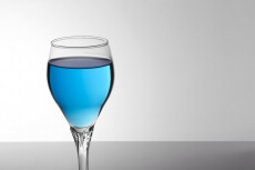 a glass of blue mocktail against white background 