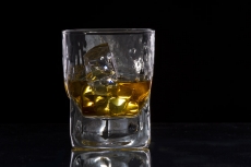 a glass of scotch with ice cubes against dark background 