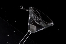 a glass of martini in motion against dark background 