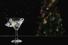 close up shot of martini drink with splash and christmas tree in the b