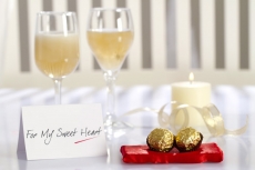 table decorated with chocolates,champagne,love note and scented candle