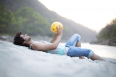 man lying on the sand playing with beach ball