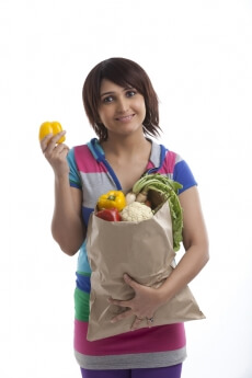woman smiling with a bag full of vegetables 