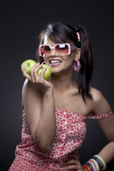 young teenager in cool shades holding two fresh green apples