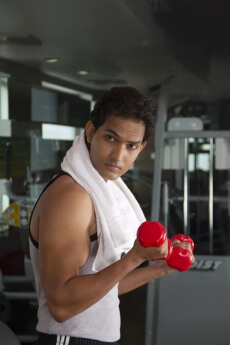 close-up portrait of a man holding red dumbbells at the gym
