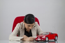 woman sitting at her office desk staring at the toy car on her table