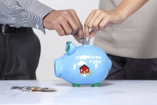 close-up of a couples hand dropping coin in a piggy bank