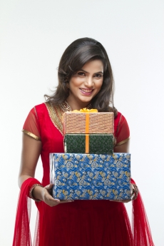 woman in ethnic wear posing for the camera holding gifts 