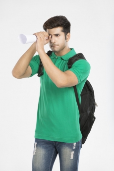 guy carrying backpack looking through rolled sheet of paper