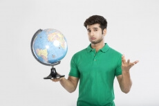 man confused while holding a desktop globe  
