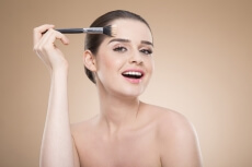 girl applying make up with brush while posing