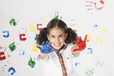 little girl in school uniform with painted hands 