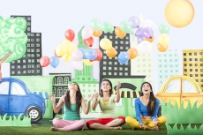 Three girls sitting on grass and floating balloons