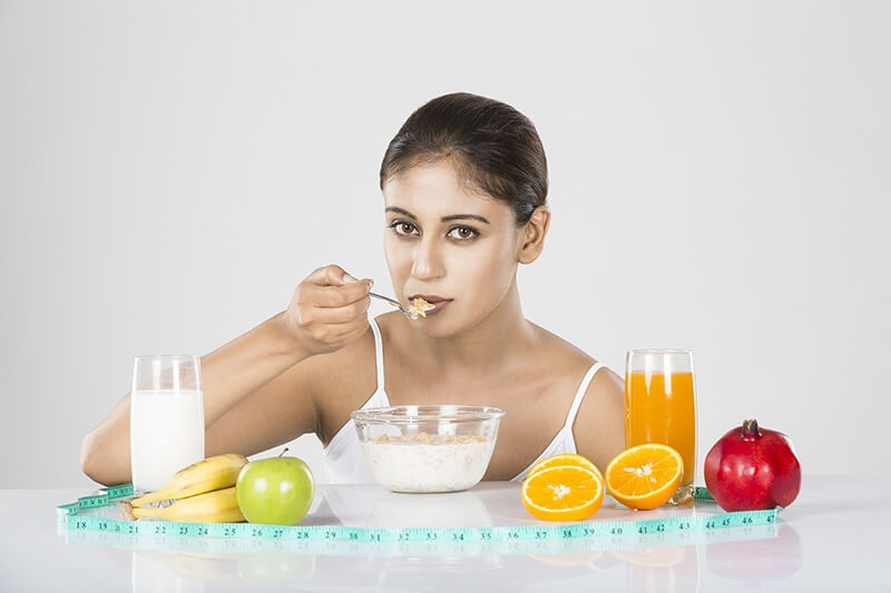 Young woman eating conflex in glass bowl with healthy fruits milk & ju